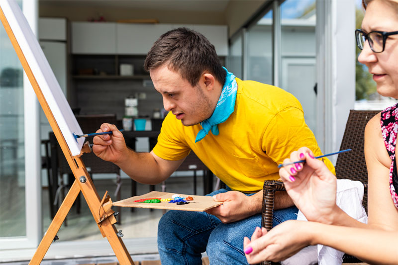 Developmental disabilities young adult painting a picture on canvas